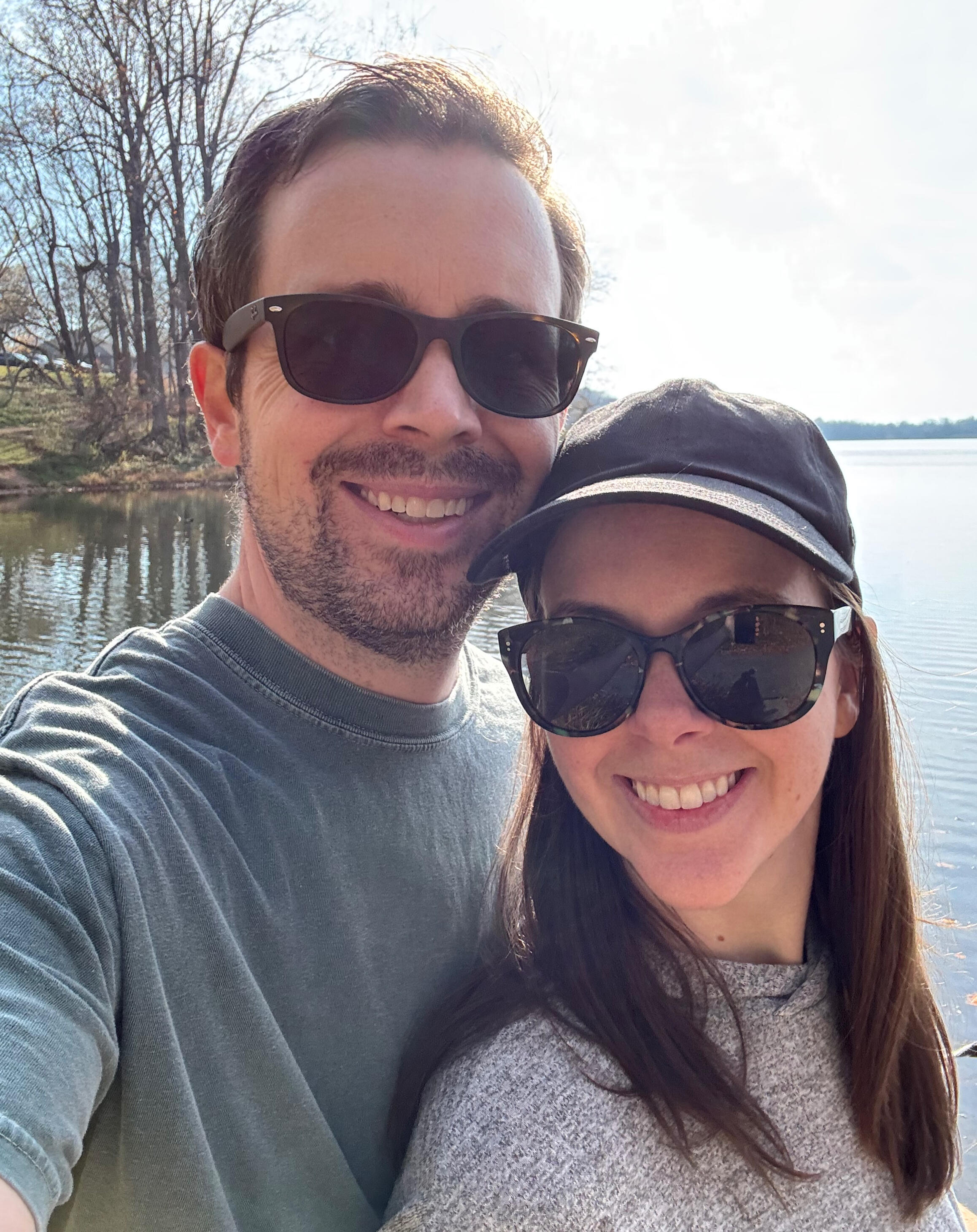 Ethan Wechtaluk smiling with his wife Courtney at a basketball game, both wearing red Washington Wizards caps and sitting in the stands with fans in the background.